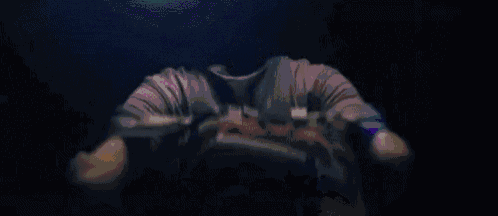 a person is tying their shoes in a dark room with a light on their feet .