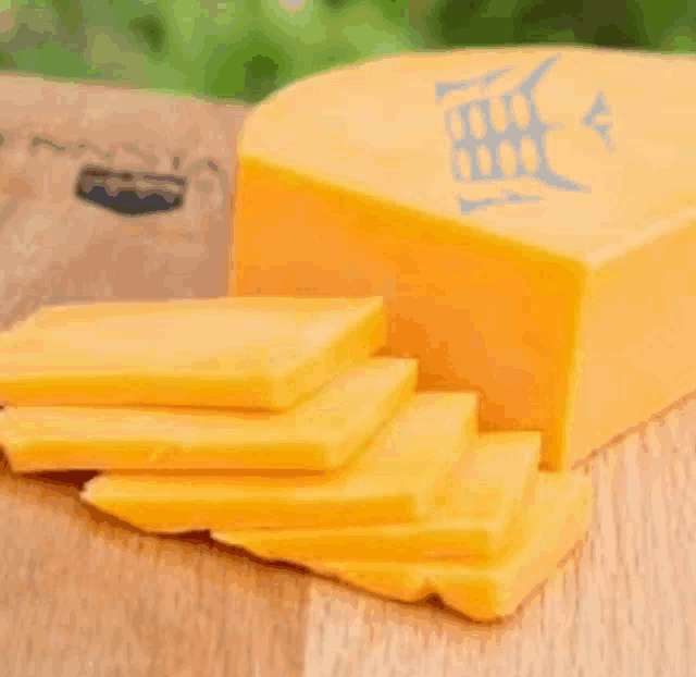 a piece of cheese is sitting on a wooden cutting board with slices of cheese on it .