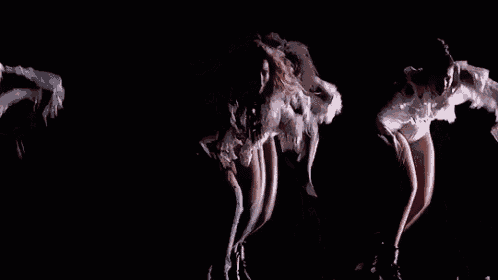 a group of women are dancing on a stage in the dark .