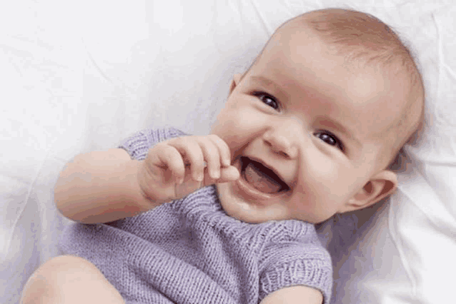 a baby in a purple sweater is laying on a bed