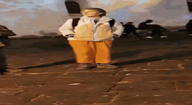 a person standing on a brick sidewalk wearing orange pants and a white jacket