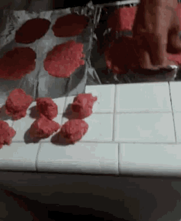 a bunch of red balls of dough are on a white counter