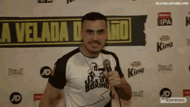 a man is holding a microphone in front of a sign that says king