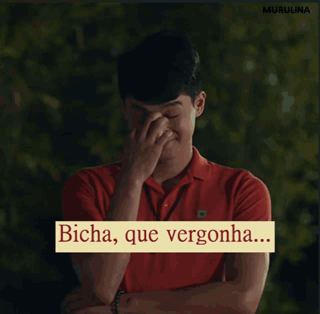 a man in a red shirt is covering his face with his hand and the words bicha que vergonha are below him