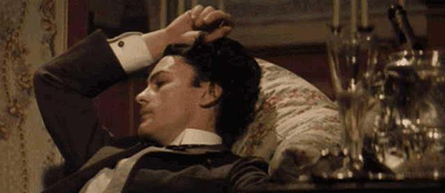 a man in a tuxedo is laying on a bed