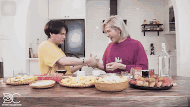 two men are sitting at a table with food and drinks and one of them is wearing a yellow shirt