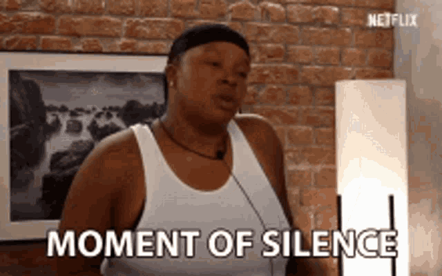 a woman is standing in front of a brick wall and says moment of silence .