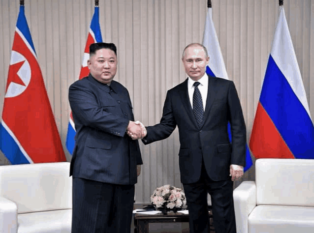 two men are shaking hands in front of flags