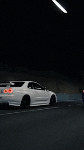 a white sports car is driving through a tunnel at night