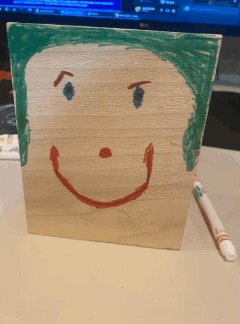 a child 's drawing of a smiling face on a wooden block