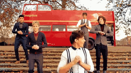 a group of men standing on steps in front of a red double decker bus .