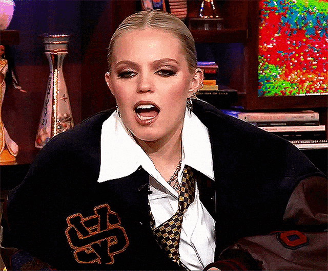 a woman wearing a jacket with a letter s on it is making a funny face