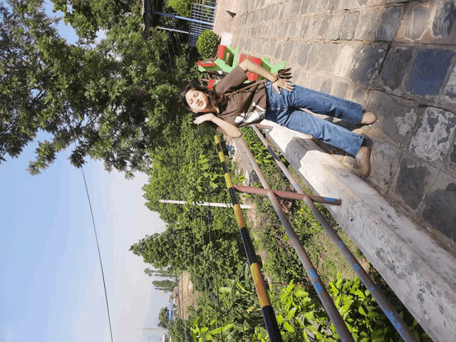 a woman is laying on a railing in a park