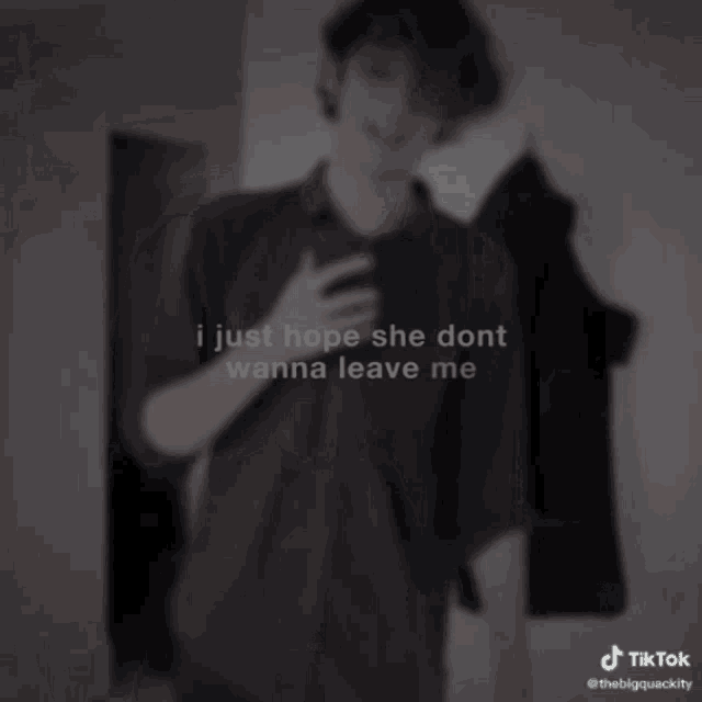 a young man in a black shirt is holding a cell phone and making a hand gesture ..