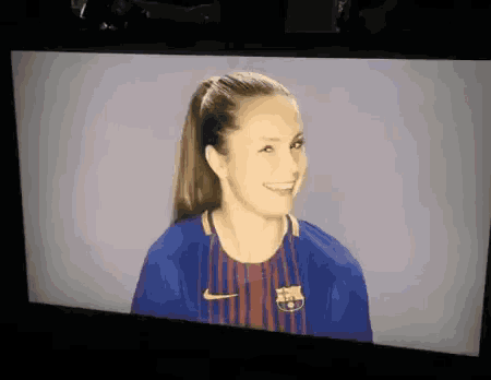 a woman wearing a barcelona jersey is smiling on a screen