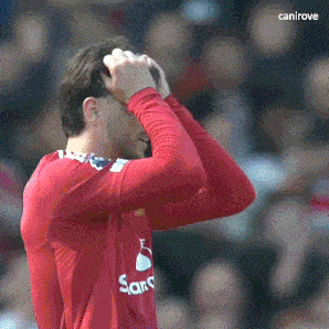 a man in a red shirt with the word sano on it holds his head