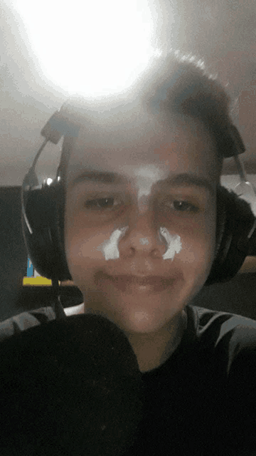 a young man with a bandage on his nose and headphones on