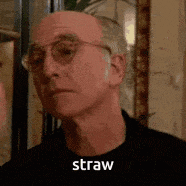 a close up of a man wearing glasses and a black shirt with the word straw written on it .