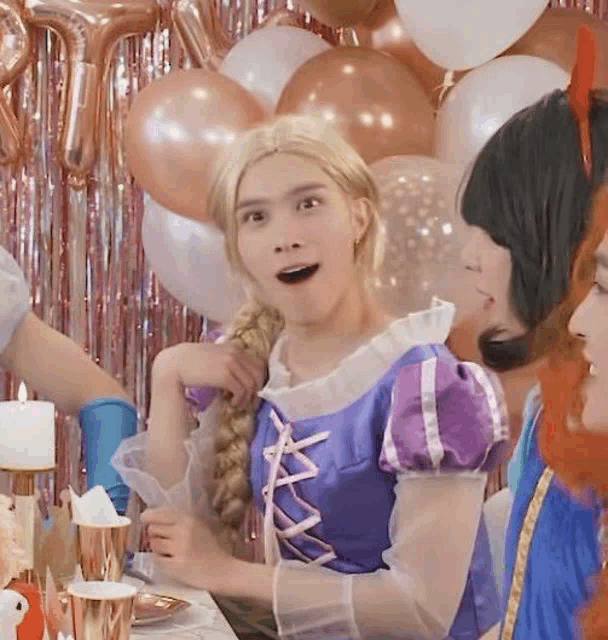 a woman in a rapunzel costume is sitting at a table with other people at a party .