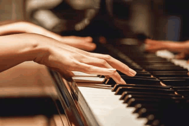 a close up of a person playing a piano with their hands on the keys