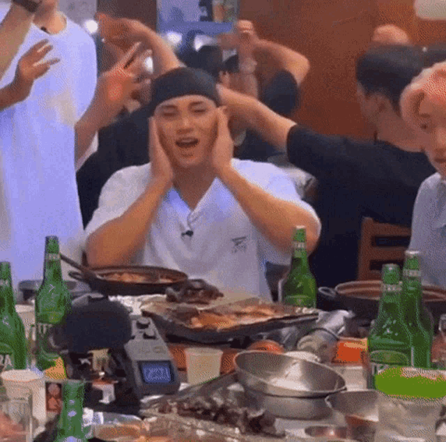 a group of people are sitting at a table with bottles of water and food .