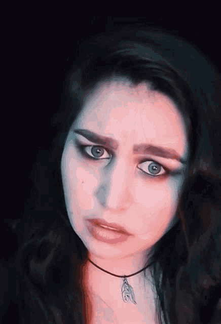 a close up of a woman 's face with a choker and a feather pendant