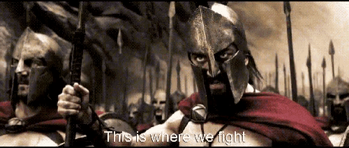 a man in a spartan helmet stands in front of a crowd with the words " this is where we fight "