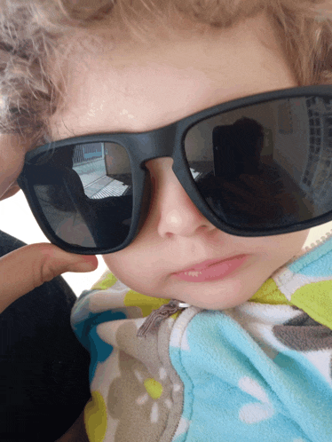 a little boy wearing sunglasses looks at the camera