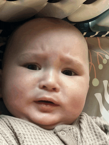 a baby is making a funny face while laying in a high chair