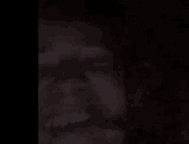 a close up of a person 's face in the dark with a black background .