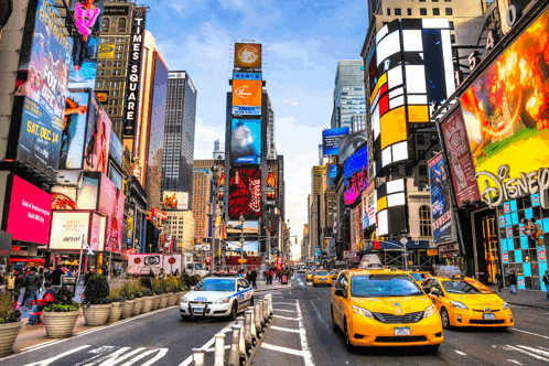 a busy city street with a times square sign in the background