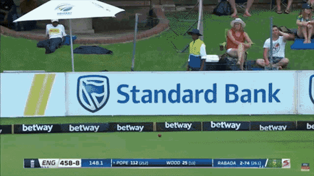 a sign for standard bank is on the side of a sports field