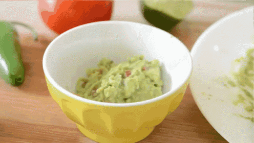 a yellow bowl of guacamole sits on a table