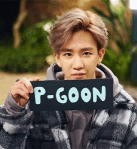 a man is holding a sign that says p-goon in front of his face .
