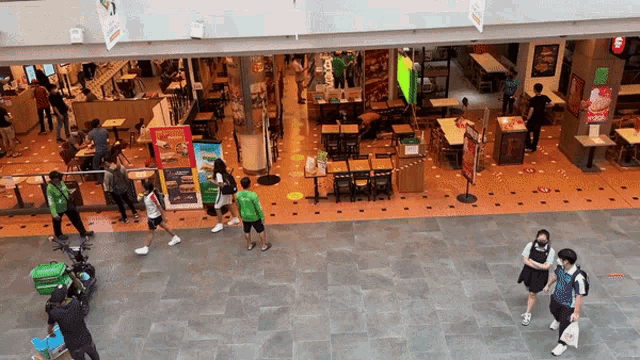 a group of people walking in front of a restaurant with a sign that says ' a ' on it