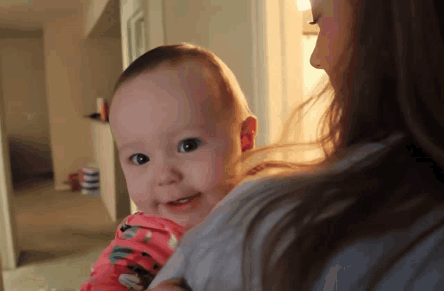 a woman is holding a baby that is smiling