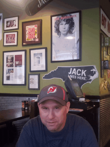 a man sitting in front of a wall with a sign that says jack lives here