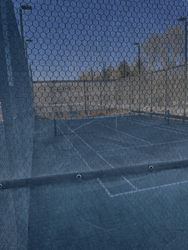 a tennis court is behind a mesh fence