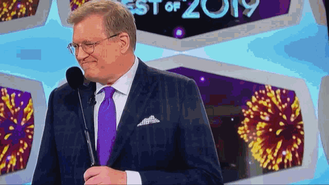 a man in a suit and tie stands in front of a sign that says ' best of 2019 '
