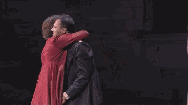 a man in a red shirt is hugging another man