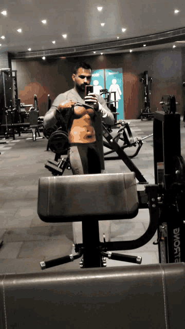 a man taking a picture of his torso in a gym with a machine that says rogue