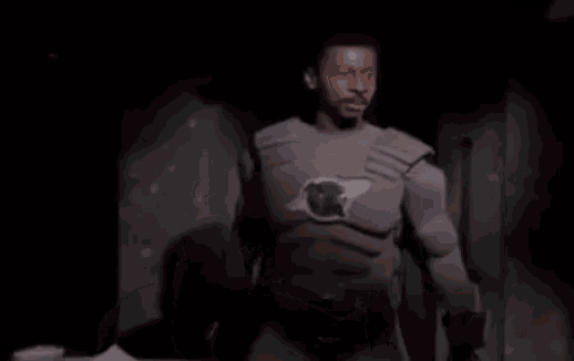 a man in a superhero costume is giving a thumbs up in the dark .