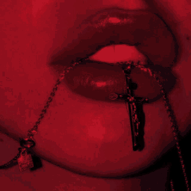a close up of a woman 's mouth with a cross necklace around her neck
