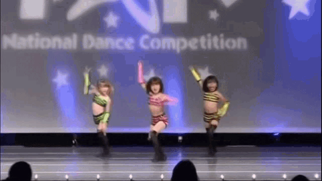 a group of young girls are dancing on a stage in front of a sign that says national dance competition .