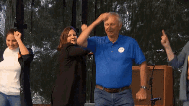 a man in a blue shirt is dancing with a woman in a white shirt and a man in a black jacket