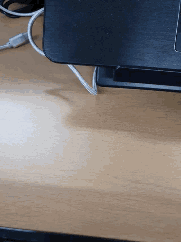 a black laptop is sitting on a wooden desk