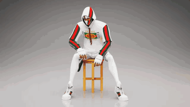 a man in a gucci hoodie is sitting on a wooden stool