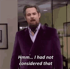 a man in a purple suit and tie is saying `` hmm ... i had not considered that ''