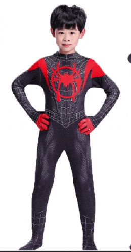 a young boy in a black and red spiderman costume stands with his hands on his hips