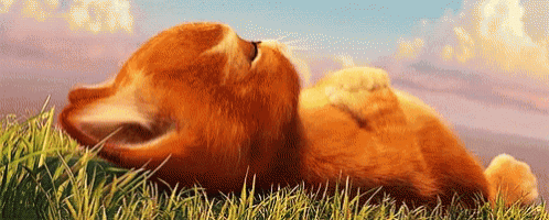 a cartoon cat is laying on its back in the grass with its mouth open .